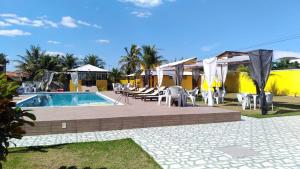 a resort with a swimming pool and tables and chairs at Pousada X in Saquarema