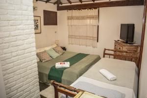 a bedroom with two beds and a tv in it at Toca Geribá in Búzios