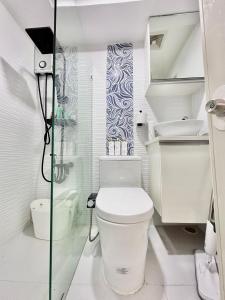 La salle de bains blanche est pourvue d'une douche et de toilettes. dans l'établissement Queen Size Studio in Cebu City, à Mandaue City