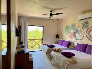 a bedroom with two beds with purple pillows at sunsteps purple room in Holbox Island