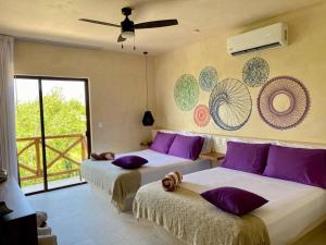 2 camas en una habitación con almohadas moradas en sunsteps purple room, en Isla Holbox