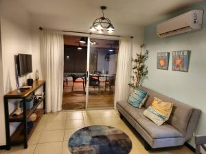 Sala de estar con sofá, TV y mesa en Condo Jaco bejuco frente al mar y casa con piscina, en Jacó