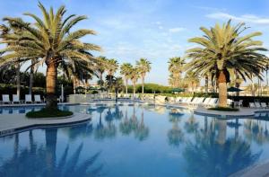 a pool with palm trees and white chairs at Cabana Isla- Hot Tub- Boat RV- Mins to DT & Beach in St. Augustine