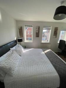 1 dormitorio con 1 cama blanca grande y ventanas en Amama's Cabin, en Great Yarmouth