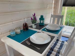 a table with plates and utensils on top of it at Comfortable holiday houses D bki in Dąbki