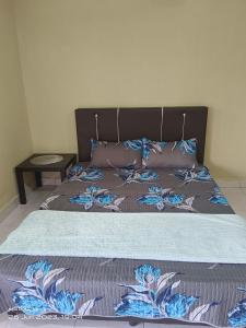 a bed with blue flowers on it in a bedroom at ALZA BUDGET ROOMStay in Pantai Cenang