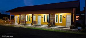 a small yellow house with lights on it at ALZA BUDGET ROOMStay in Pantai Cenang