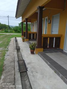 a house with a porch with a fence in front of it at ALZA BUDGET ROOMStay in Pantai Cenang