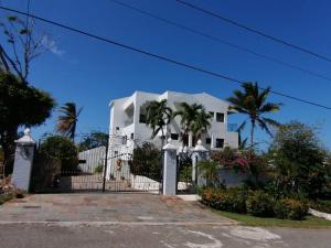 una casa blanca con una valla y palmeras en White House Mansion en San Felipe de Puerto Plata