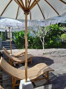 two chairs and an umbrella on a patio at Kala Surf Camp in Uluwatu