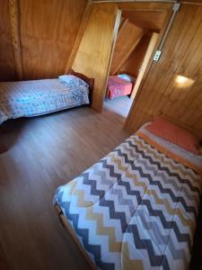 1 dormitorio con 2 camas en una cabaña de madera en Cabaña Los Pinos, en Chonchi