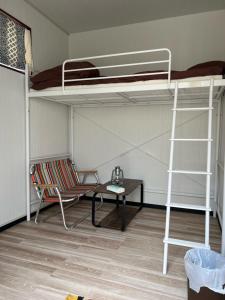 Zimmer mit 2 Etagenbetten, einem Tisch und einem Stuhl in der Unterkunft One World Activity in Kumejima