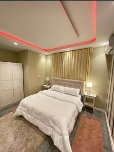 a bedroom with a large white bed with a red stripe on the ceiling at Al Muftaha Apartment in Abha