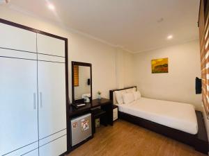 a small bedroom with a bed and a mirror at Rising Dragon Hotel in Hanoi