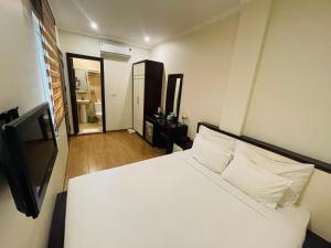 a bedroom with a white bed and a television at Rising Dragon Hotel in Hanoi
