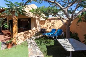 patio z 2 krzesłami, stołem i drzewem w obiekcie Vivienda Vacacional Orquidea w Corralejo