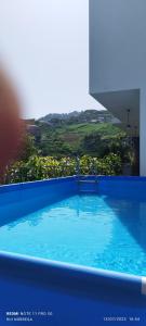 a blue swimming pool with a view of a hill at D Henriques House in Câmara de Lobos