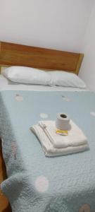 ein Bett mit blauer Decke mit einer Tasse und einer Kerze darüber in der Unterkunft HOSPEDAJE GIMAJA in Villa Rica