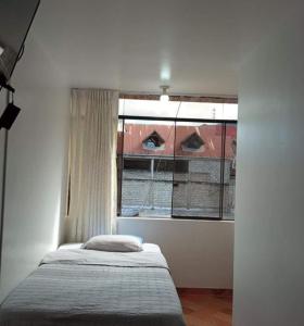 ein Schlafzimmer mit einem Bett und einem großen Fenster in der Unterkunft HOSPEDAJE GIMAJA in Villa Rica