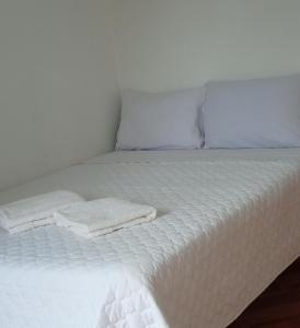uma cama branca com cobertores brancos e almofadas em HOSPEDAJE GIMAJA em Villa Rica