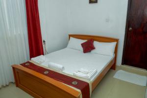 ein kleines Bett in einem Zimmer mit einem roten Vorhang in der Unterkunft Villa Hotel in Trincomalee
