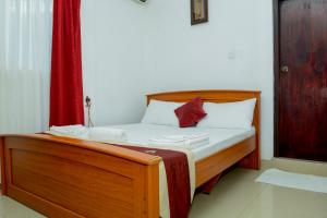 a bed with white sheets and a red curtain at Villa Hotel in Trincomalee