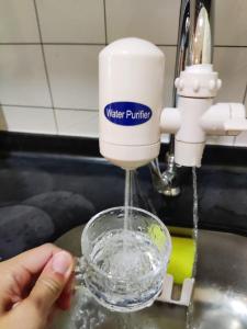 a person is drinking water out of a glass at JoJo Homestay Tiara Residence in Desaru