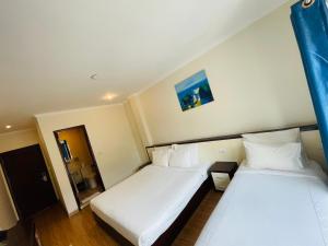 two beds in a hotel room with white sheets at Rising Dragon Hotel in Hanoi