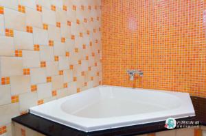 鵝鑾的住宿－龍園居民宿，浴室铺有橙色和白色瓷砖,配有浴缸。