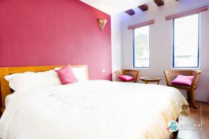 um quarto com uma cama branca e paredes cor-de-rosa em Long Yuan Ju Homestay em Eluan