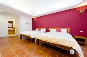 um quarto com 2 camas e uma parede roxa em Long Yuan Ju Homestay em Eluan
