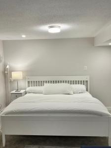 1 dormitorio blanco con 1 cama con cabecero blanco en The Oasis Lounge by Luke 1913, en Ottawa