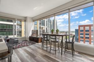 een woonkamer met een tafel en stoelen en een groot raam bij Chic 2BR Condo in Vibrant Downtown Calgary in Calgary