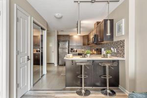 a kitchen with brown cabinets and a counter with stools at City Centre Retreat - 1BR Condo with Desk in Calgary