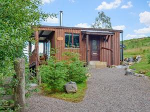 a small wooden cabin with a gravel driveway at Glenkens Lodge in Dalry