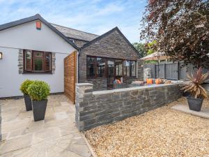 a home with a brick retaining wall and a patio at Dant Y Llew - Uk42790 in Bow Street