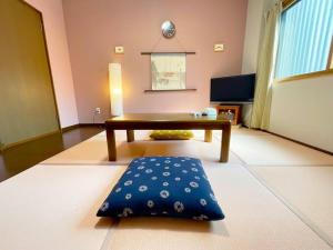Sushi House في شينغو: غرفة معيشة مع طاولة وسجادة زرقاء