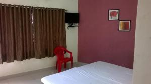 una sedia rossa seduta accanto a un letto in una camera da letto di St Xavier always a Chennai