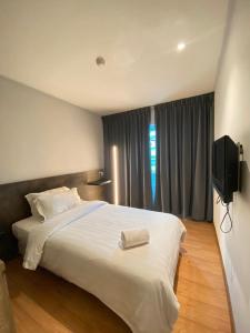 a bedroom with a large white bed and a flat screen tv at Merchant Express Bintulu in Bintulu