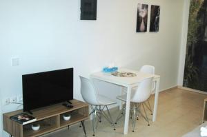 A L' AISE STUDIOS في Apolpaina: غرفة معيشة مع طاولة مع كراسي وتلفزيون