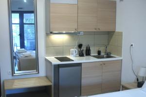 A L' AISE STUDIOS في Apolpaina: مطبخ صغير مع دواليب خشبية ومغسلة