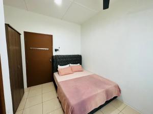 a bedroom with a bed with pink pillows on it at Macagawa Homestay in Tawau