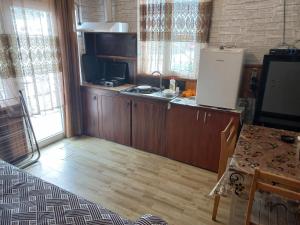 a kitchen with wooden cabinets and a refrigerator and a table at Guest House Roman/Gonio in Gonio