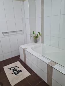 a white bathroom with a tub and a rug at Dashwood Dreaming - Room in Shared Apartment in Darwin