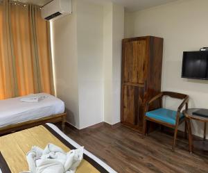 a room with a bed and a chair and a television at SeaScape Port Blair in Port Blair
