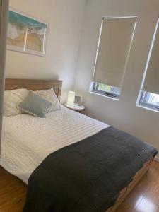 1 dormitorio con 1 cama y 2 ventanas en Nor Easter Townhouse, en Caringbah