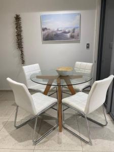 comedor con mesa y sillas blancas en Nor Easter Townhouse, en Caringbah