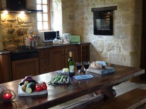 una cocina con una mesa con copas de vino y verduras en Château à Gourdon dans le Lot, en Gourdon-en-quercy