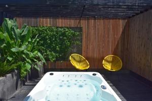 bañera en un patio con 2 sillas amarillas en Fare Bambou, en Gujan-Mestras