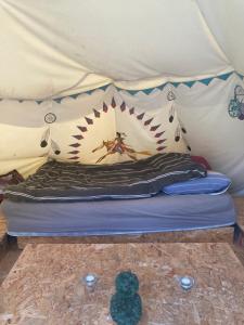 a bed in a tent with a man on it at Tipis La Paix retrouvée in Tourrette-Levens